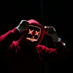 a hacker wearing a red hoodie and neon mask