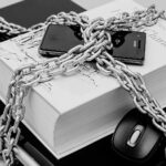 laptop, mouse, book and cellphone bound in chains