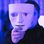 hacker holding their mask in front of their face