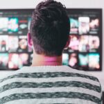 person sitting on the sofa and watching tv