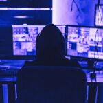 hacker sitting in basement with multiple screens
